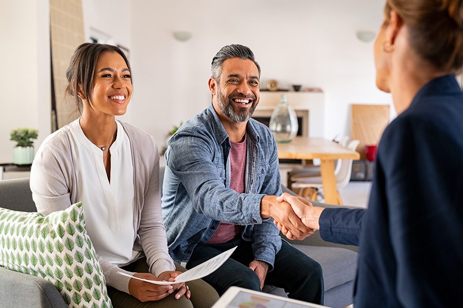 Home Warranty Protection - Couple Shaking Hands With Warranty Advisor at Their Home While Sitting in the Living Room